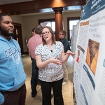 Student presenting their poster to a guest at the Graduate Showcase